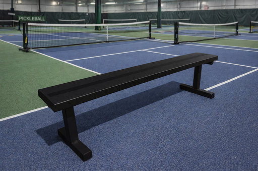 Black bench on an indoor pickleball court with a net in the background