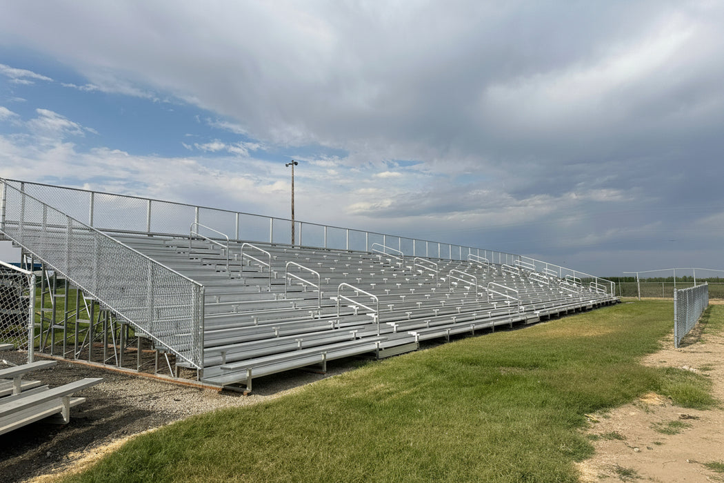 Metal bleachers on a grassy field with a cloudy sky