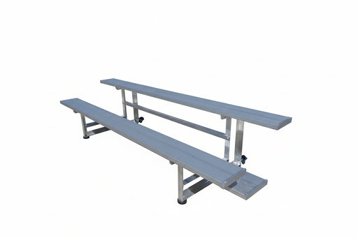 Two metal bleachers on a concrete floor with a warehouse in the background