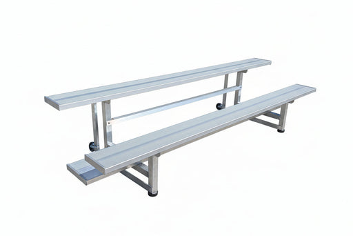 Aluminum bleachers on a concrete surface with a trailer in the background